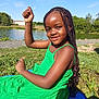 Tiana participe au concours pour gagner de l'argent avec cette photo : child, girl, green_dress, braided_hair, outdoor, river, grass, blue_sky, sunlight, smile, playful_pose, nature, blanket, summer, happy, young, portrait, casual, scenic, daytime