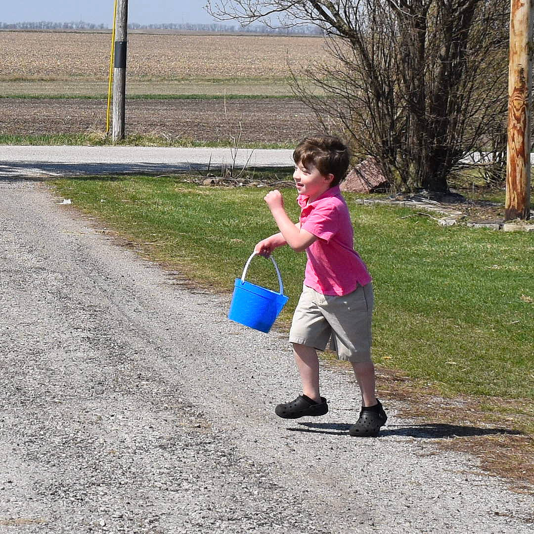 Brently is registered to the contest to win money with this photo: asphalt, bag, electric_blue, footwear, grass, happy, human_leg, leisure, luggage_and_bags, people_in_nature, person, plant, recreation, road, road_surface, sidewalk, soil, toddler, travel, tree