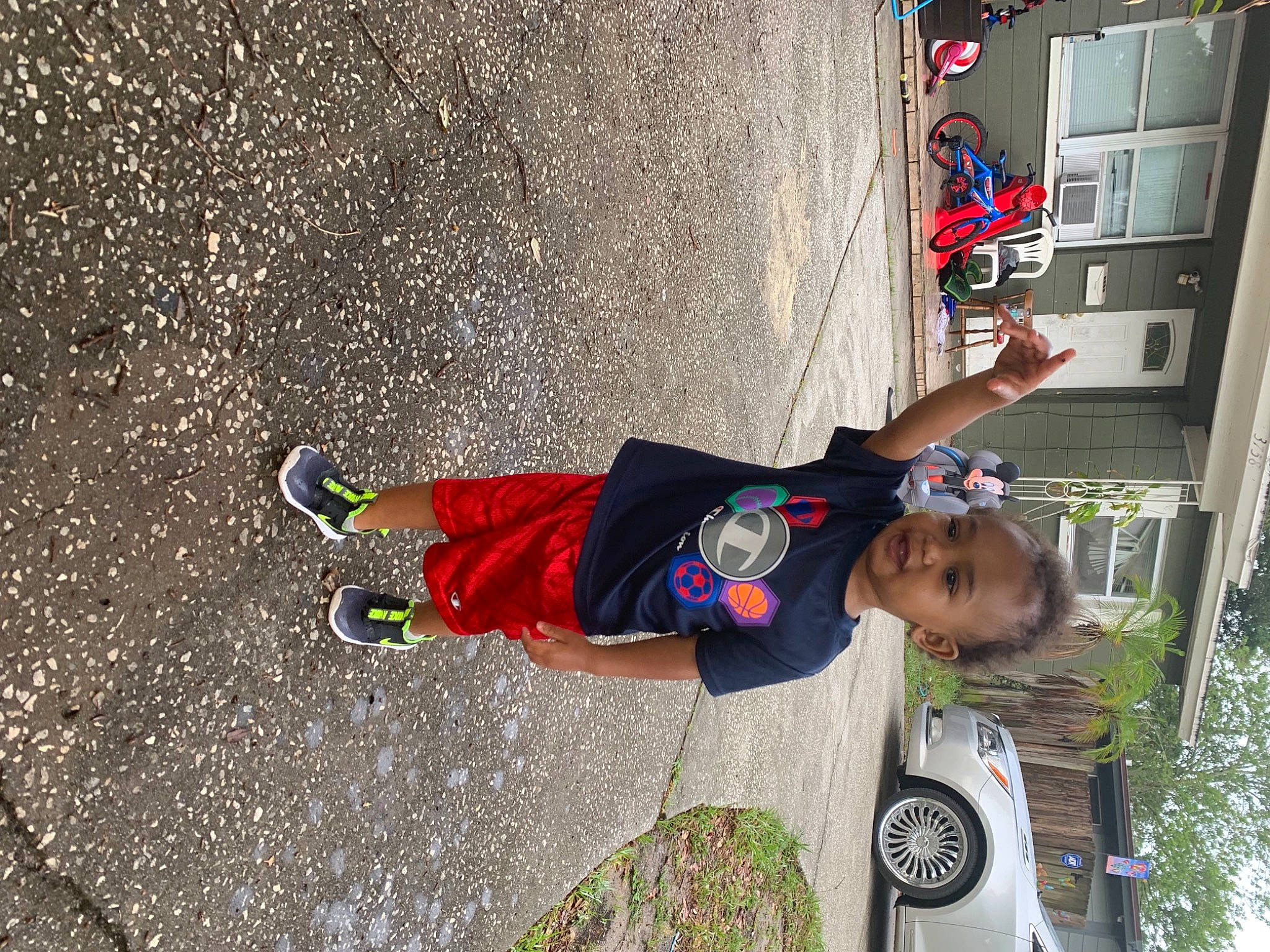 Zeus is registered to the contest to win money with this photo: asphalt, car, concrete, fun, hat, leisure, person, plant, recreation, road, sidewalk, sneakers, street_fashion, t_shirt, tire, toddler, tree, vehicle, walking_shoe, wall