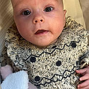 Bonnie is registered to the contest to win money with this photo: baby, infant, face, eyes, expression, clothing, patterned_dress, hand, plush_toy, soft_texture, blanket, closeup, cute, child, newborn, portrait, indoors, skin, head, lying_down