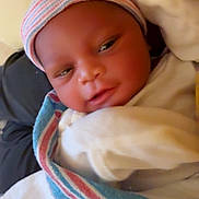 Jakai is registered to the contest to win money with this photo: baby, bed, blanket, child, close_up, cuddled, eyes_open, face, hat, indoors, infant, newborn, photography, pillow, portrait, serious_expression, striped_hat, swaddled, white_clothing, wrapped