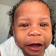 Jaejuan is registered to the contest to win money with this photo: baby, close_up, face, curly_hair, indoor, child, expression, open_mouth, teeth, skin, person, white_clothing, cute, portrait, young, infant, eye, head, mouth, human