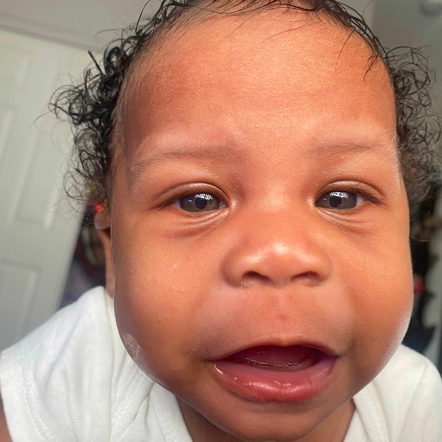 Jaejuan is registered to the contest to win money with this photo: baby, child, close_up, curly_hair, cute, expression, eye, face, head, human, indoor, infant, mouth, open_mouth, person, portrait, skin, teeth, white_clothing, young