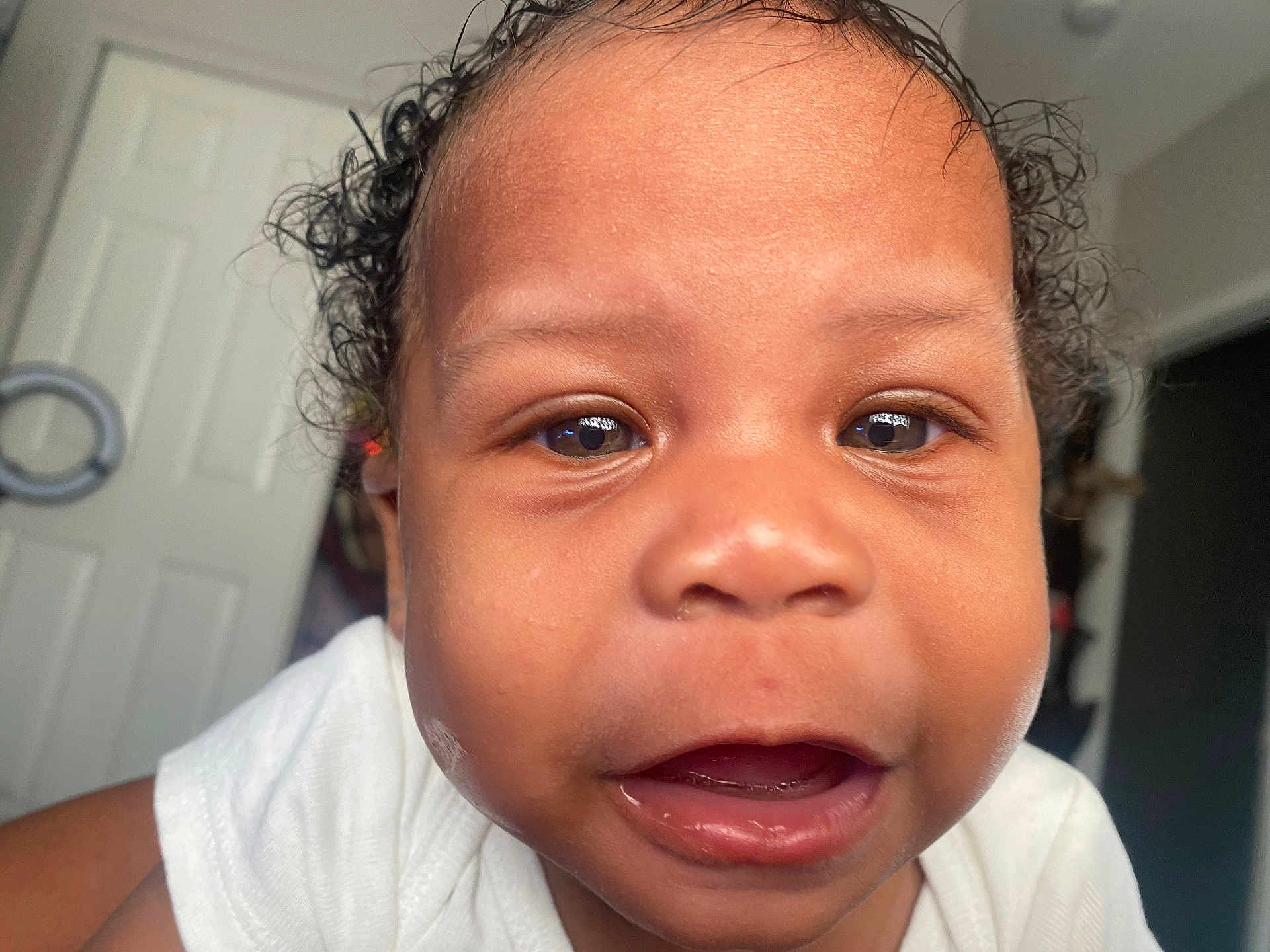 Jaejuan is registered to the contest to win money with this photo: baby, close_up, face, curly_hair, indoor, child, expression, open_mouth, teeth, skin, person, white_clothing, cute, portrait, young, infant, eye, head, mouth, human