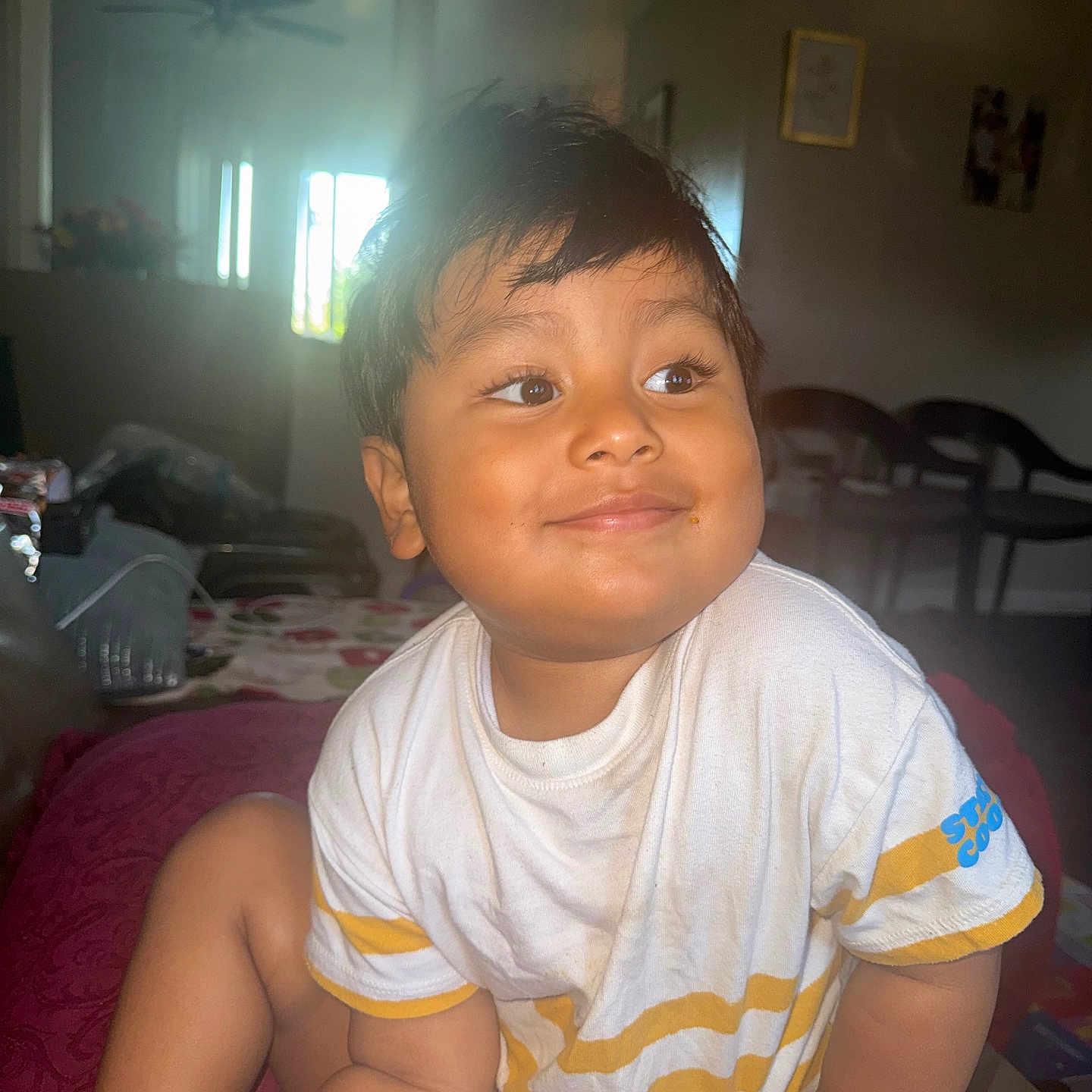 Carlosdorian joined the competition — help win amazing prizes! child, toddler, smiling, portrait, sitting, indoors, home, bedroom, white_shirt, striped_shirt, short_hair, face, eyes, sunlight, window, furniture, bed, blanket, casual_clothing, photograph