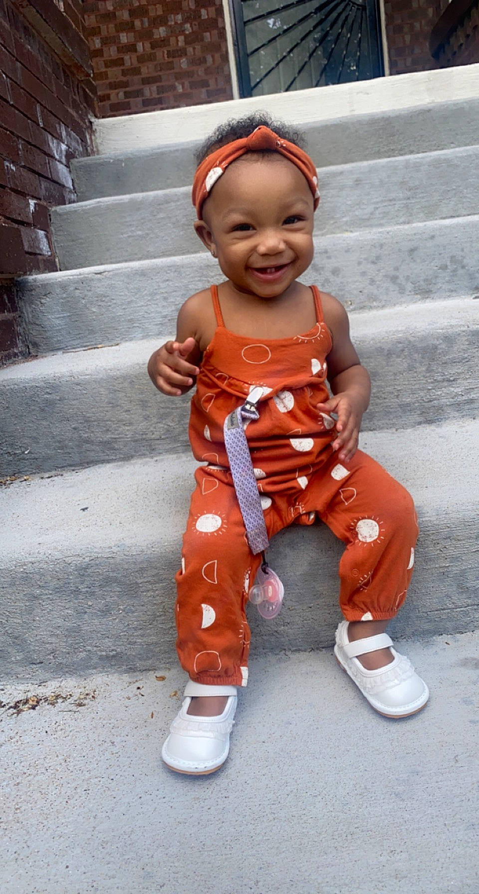 Kirah is registered to the contest to win money with this photo: baby, baby_toddler_clothing, child, costume, face, footwear, happy, head, joy, orange, outerwear, pattern, peach, person, personal_protective_equipment, pink, shoe, sleeve, smile, street_fashion