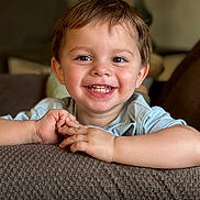 Damian joined the competition — help win amazing prizes! child, toddler, smiling, happy, portrait, face, eyes, teeth, braces, brown_hair, short_hair, blue_shirt, arms, hands, indoor, living_room, couch, sofa, blanket, closeup