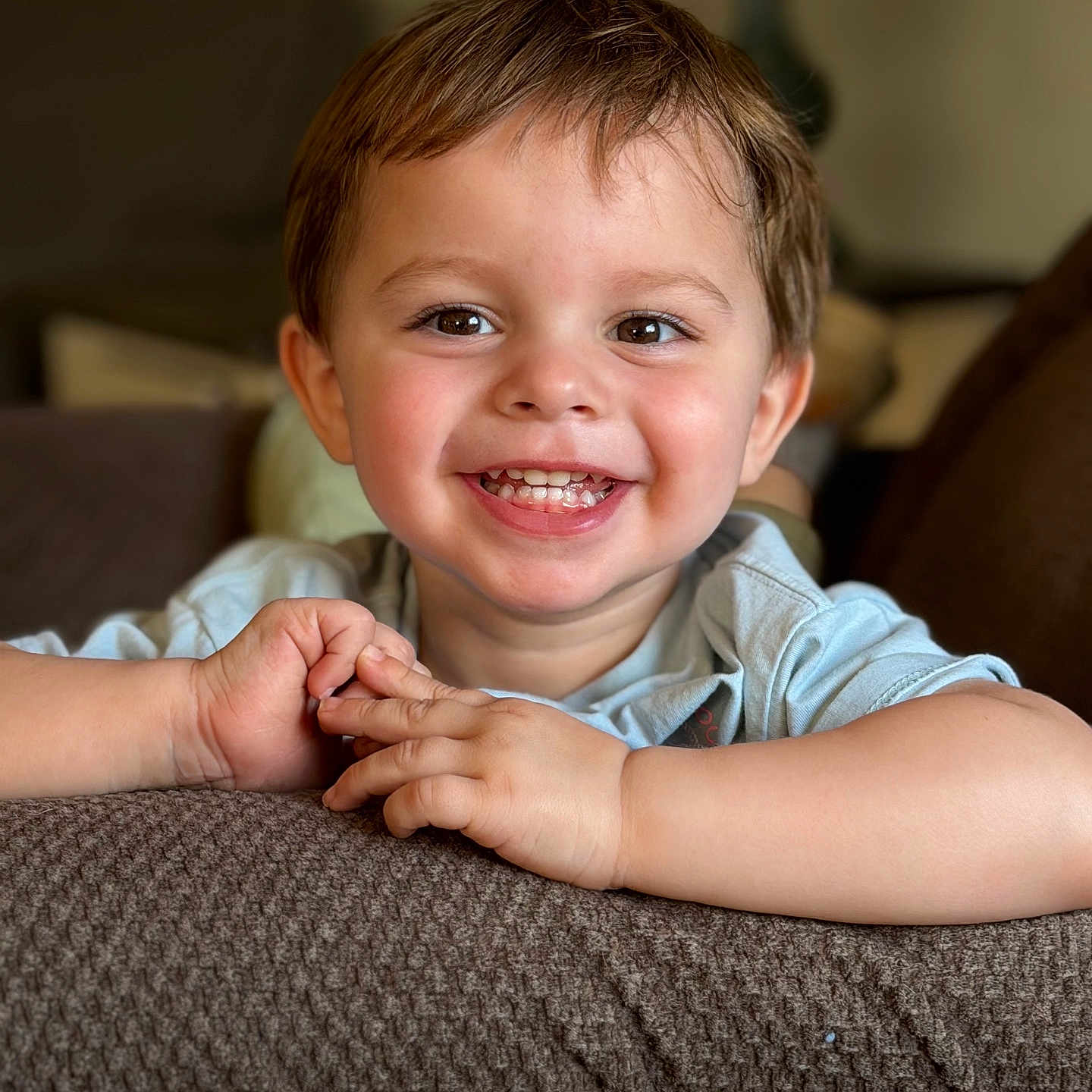 Damian joined the competition — help win amazing prizes! child, toddler, smiling, happy, portrait, face, eyes, teeth, braces, brown_hair, short_hair, blue_shirt, arms, hands, indoor, living_room, couch, sofa, blanket, closeup