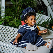 J'Alani joined the competition — help win amazing prizes! child, toddler, girl, smiling, portrait, sitting, dress, navy_blue, bonnet, headband, shoes, wicker_sofa, couch, cushions, plants, indoor, tropical, sunlight, happy, fashion