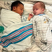 Maritza is registered to the contest to win money with this photo: newborn, baby, sleeping, crib, blanket, onesie, striped, infant, peaceful, cute, resting, twin, soft_lighting, bed, child, baby_bedding, indoors, portrait, cozy, sleep