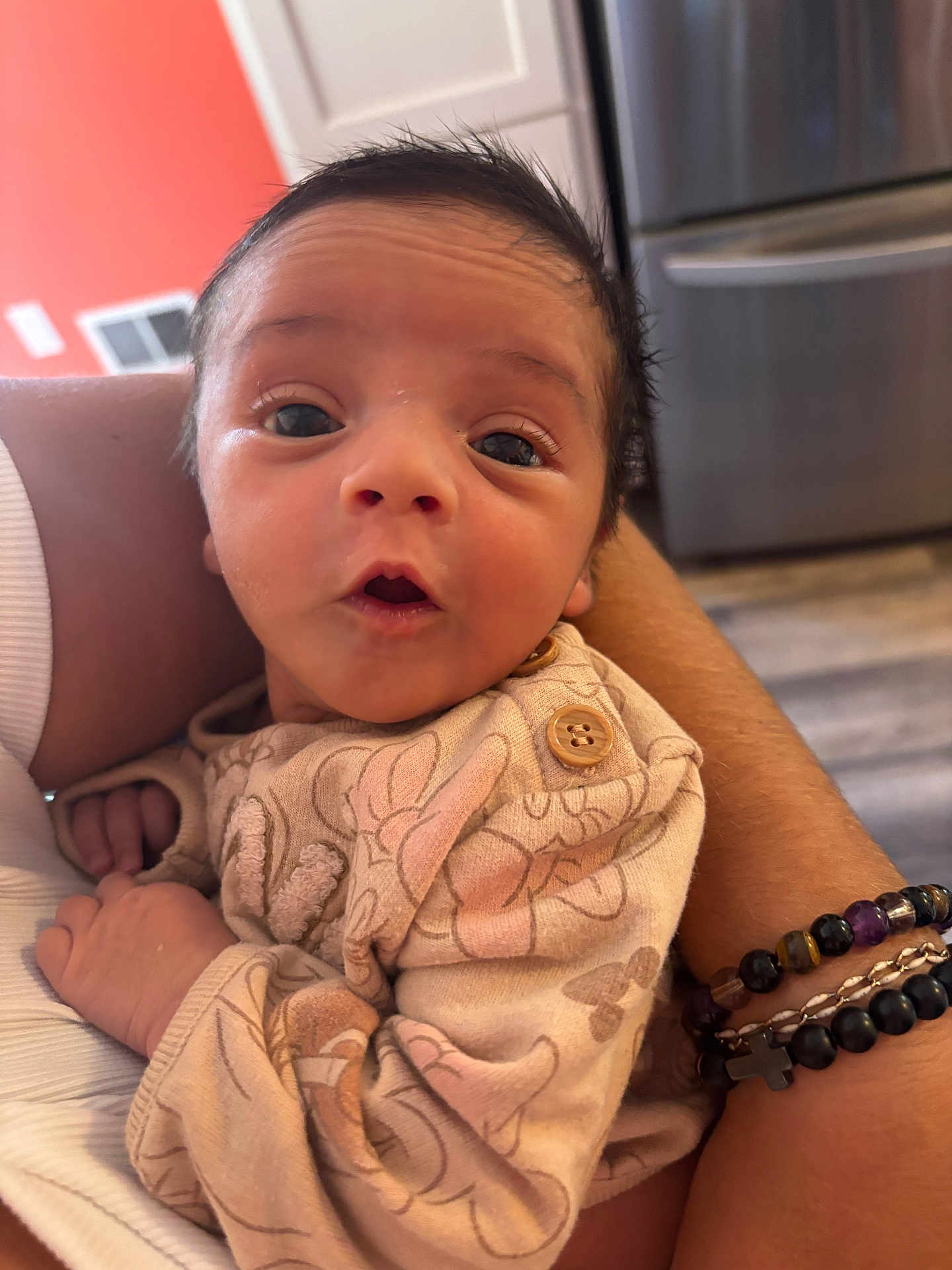 Maritza is registered to the contest to win money with this photo: baby, infant, person, clothing, hand, arm, bracelet, face, eyes, expression, indoors, kitchen, furniture, pattern, sleeve, skin, human, holding, cute, newborn