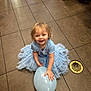 toddler, child, balloon, blue_dress, smiling, floor, tile, indoor, person, hand, face, hair, footwear, drain, light, shadow, clothing, happy, sitting, play