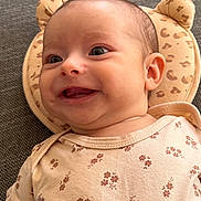 Rose participe au concours pour gagner de l'argent avec cette photo : baby, smiling, infant, onesie, floral_pattern, cushion, bear_shape, cute, happy, face, head, skin, clothing, lying_down, indoors, texture, fabric, closeup, child, person