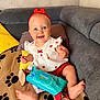 baby, blanket, blue_eyes, child, couch, cute, footwear, happy, headband, indoors, infant, minnie_mouse_sandals, pampers_wipes, paw_prints, pillows, red_bow, red_shorts, sitting, smiling, white_dress