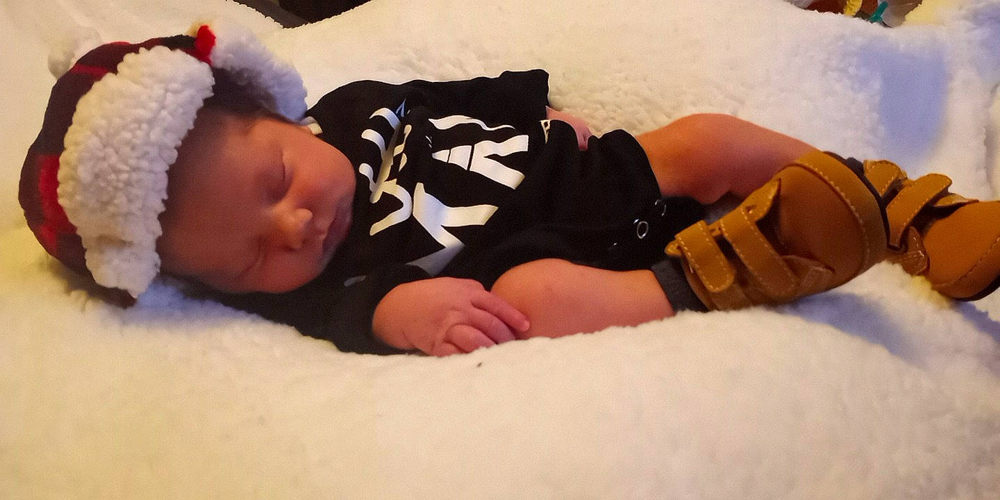 Angelo is registered to the contest to win money with this photo: arm, baby, baby_sleeping, baby_toddler_clothing, child, comfort, elbow, eye, finger, foot, gesture, hand, head, human_body, human_leg, linens, person, skin, thigh, toddler