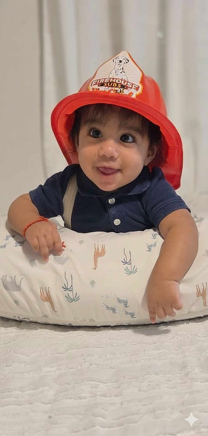 Charles Alexander joined the competition — help win amazing prizes! baby, child, firefighter_hat, red_hat, cushion, animal_print, tongue_out, curious_eyes, smile, infant, indoor, cute, playful, short_sleeves, pale_background, toy_hat, person, young_child, happy, face