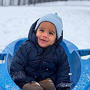 Charles Alexander is registered to the contest to win money with this photo: blue_jacket, boots, child, cold_weather, cute, face, fun, happy, knit_hat, mittens, outdoor, park, play, seasonal, sled, smiling, snow, snowflakes, toddler, winter
