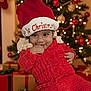 baby, child, christmas_hat, red_clothing, knitwear, christmas_tree, christmas_lights, presents, holiday, festive, smiling, indoors, decorations, cute, portrait, seasonal, holiday_cheer, warm, celebration, festivity