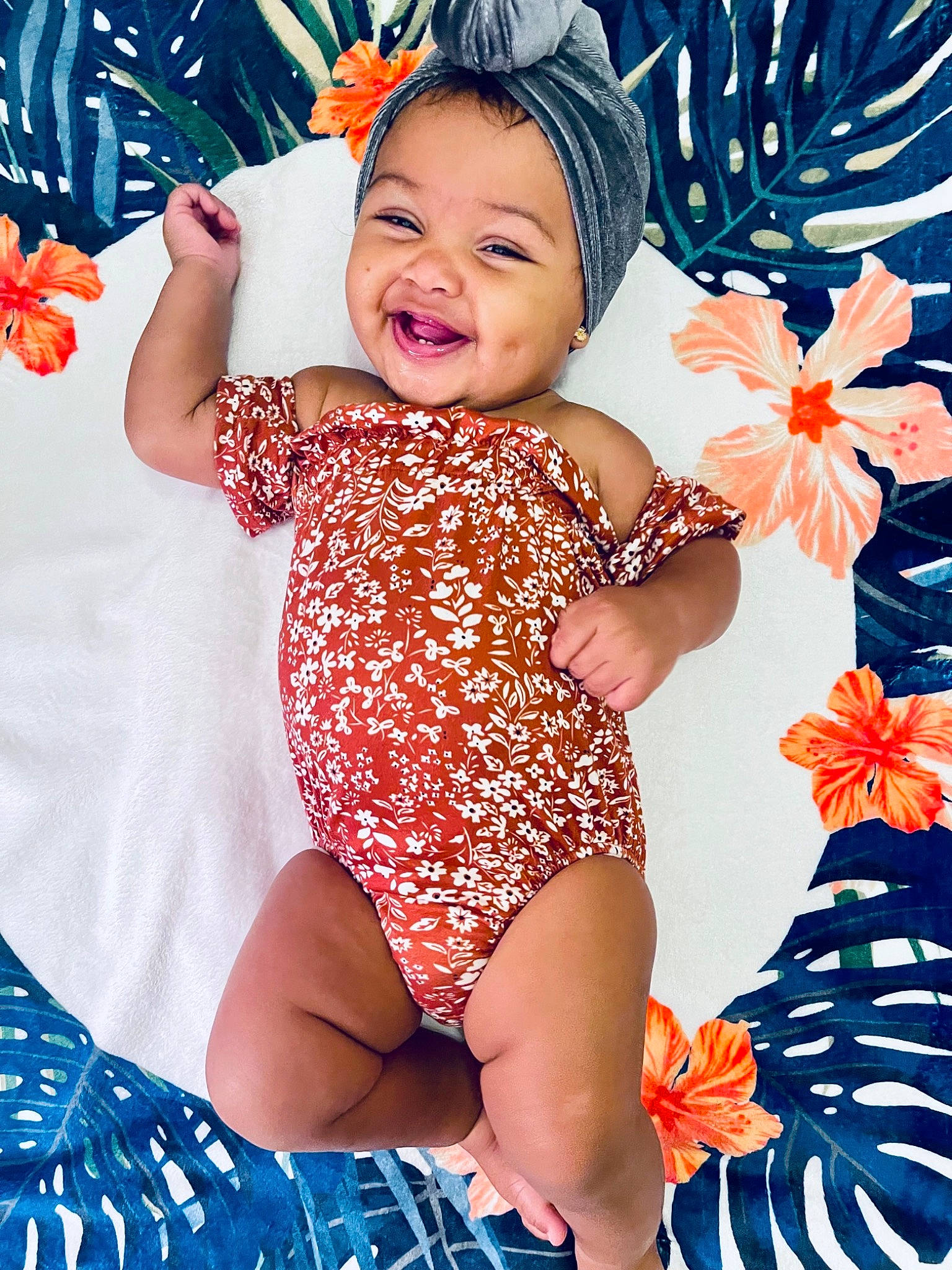 Indie is registered to the contest to win money with this photo: baby_toddler_clothing, beauty, blue, child, facial_expression, finger, flower, happy, hat, nail, orange, pattern, people_in_nature, person, petal, photograph, pink, skin, smile, thigh