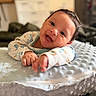 baby, infant, smiling, happy, pillow, soft_texture, pajamas, indoors, cute, lying_down, hand, face, child, cozy, blurred_background, young, skin, head, expression, comfortable