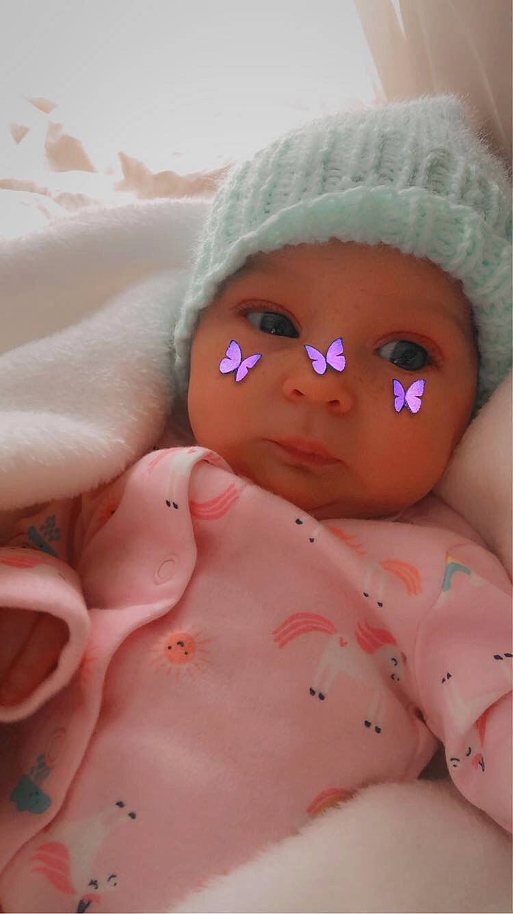 Avery is registered to the contest to win money with this photo: baby, cap, cheek, chin, doll, eye, eyebrow, eyelash, face, head, headwear, human_body, iris, linens, lip, mouth, nose, person, pink, skin
