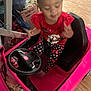 Hartley is registered to the contest to win money with this photo: child, toy_car, pink, indoor, floor, wood_floor, red_shirt, polka_dot_leggings, black_seat, steering_wheel, clutter, box, cables, hand, foot, person, playing, blurry, casual_clothing, young
