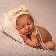 Shelby participe au concours pour gagner de l'argent avec cette photo : baby, newborn, sleeping, hat, pillow, blanket, soft_texture, peaceful, infant, resting, cute, portrait, cozy, warm_tones, skin, child, knitted_hat, pom_poms, flower, toddler