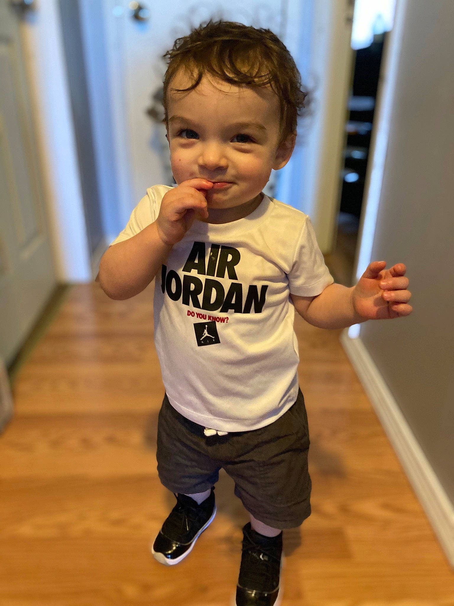 Jordan is registered to the contest to win money with this photo: baby_toddler_clothing, cheek, child, door, face, flooring, fun, gesture, happy, hardwood, joint, knee, person, sleeve, smile, sportswear, standing, t_shirt, thumb, toddler