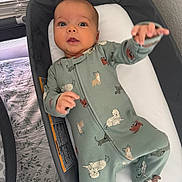 Kaisen is registered to the contest to win money with this photo: baby, infant, onesie, baby_bassinet, dog_pattern, reaching_hand, curious_expression, indoor, window_light, crib, blanket, sleepwear, cute, child, person, footed_pajamas, soft_toys, home, nursery, resting