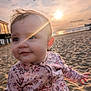 baby, child, face, sunlight, sunset, beach, sand, jacket, floral, outdoor, portrait, cute, person, smiling, nature, warm_light, happy, young, closeup, sky