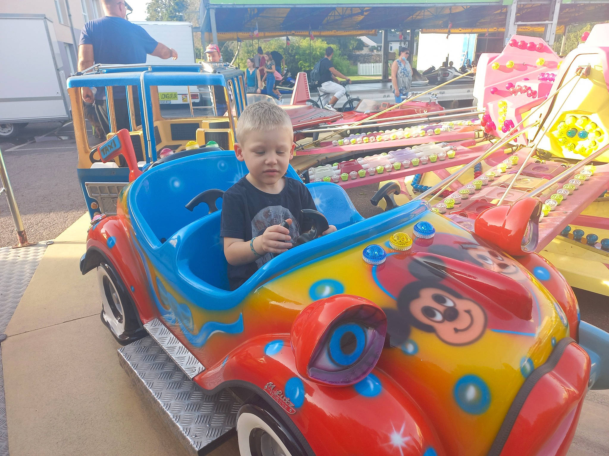 Emilien a rejoint le concours — aidez-le/la à gagner de superbes lots ! amusement_ride, automotive_design, automotive_exterior, automotive_tire, automotive_wheel_system, bumper, car, classic, electric_blue, fun, leisure, motor_vehicle, outdoor_recreation, person, recreation, riding_toy, shorts, tire, toddler, vehicle