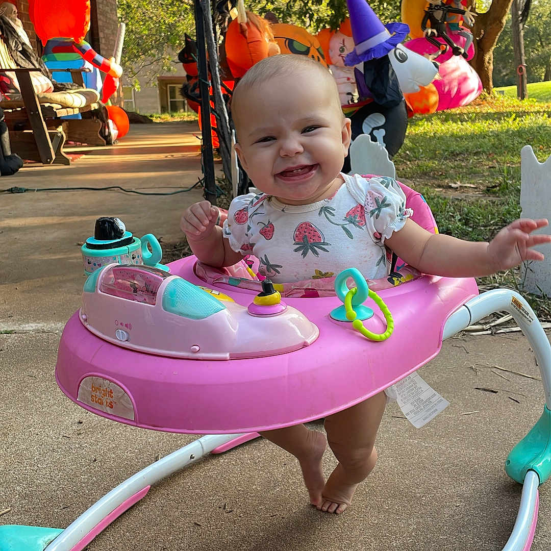 Vivian is registered to the contest to win money with this photo: baby, child, clothing, costume, decorations, foot, grass, halloween, happy, outdoor, plastic, playtime, porch, pumpkin, seasonal, smiling, sunlight, toy, tree, walker
