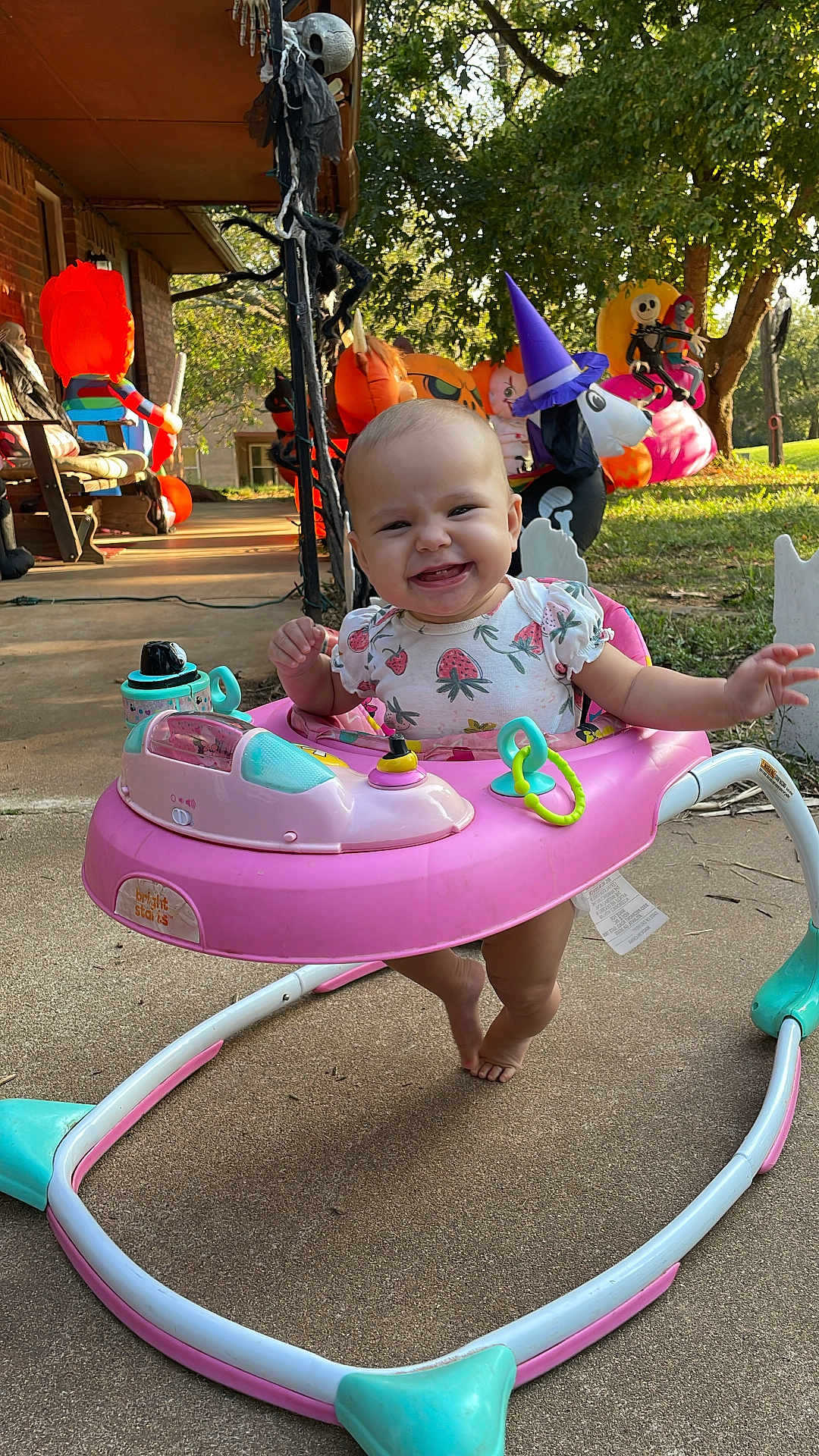 Vivian is registered to the contest to win money with this photo: baby, walker, smiling, outdoor, halloween, decorations, porch, toy, grass, tree, sunlight, pumpkin, costume, plastic, playtime, child, foot, clothing, happy, seasonal
