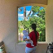 Juliann a rejoint le concours — aidez-le/la à gagner de superbes lots ! baby, balcony, building, casual_clothing, child, clouds, daylight, greenery, holding, long_hair, outdoor, plants, red_shirt, scenery, shorts, sky, trees, white_hoodie, window, woman