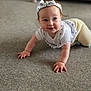 baby, carpet, casual_clothing, child, crawling, cute, floor, hands, happy, headband, home, indoor, living_room, person, portrait, smiling, sofa, white_top, yellow_pants, young_child
