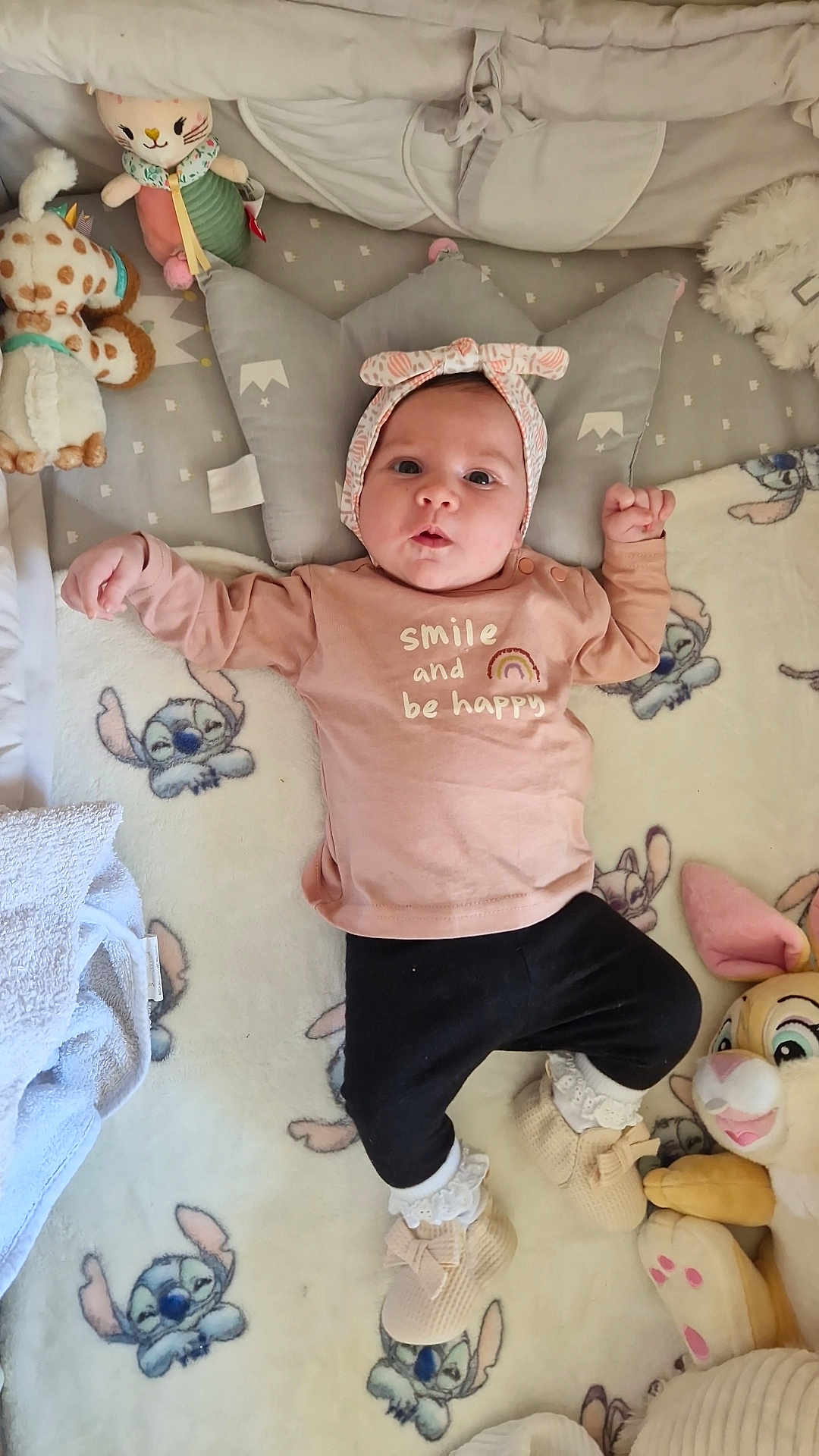 Kataleya a rejoint le concours — aidez-le/la à gagner de superbes lots ! baby, infant, blanket, plush_toy, headband, shirt, smile, happy, lying_down, cute, child, soft_toys, footwear, pillow, bedroom, cozy, indoors, toddler, expression, clothing