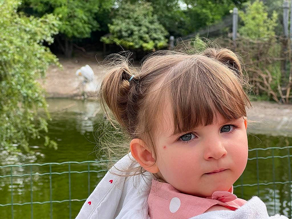 Maëlys participe au concours pour gagner de l'argent avec cette photo : bangs, botany, brown_hair, eye, eyebrow, eyelash, eyewear, fashion_accessory, fun, grass, happy, lake, leisure, lip, neck, people_in_nature, person, plant, toddler, tree