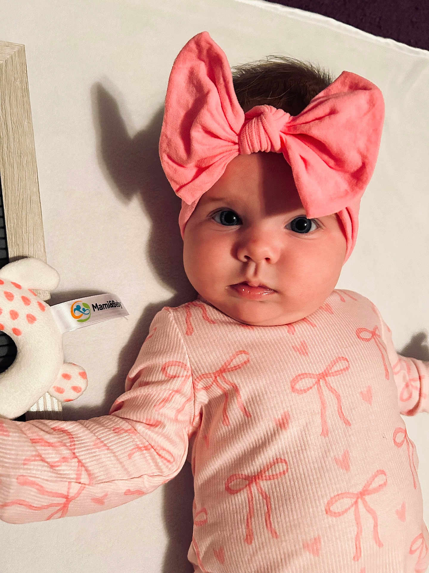 Addison joined the competition — help win amazing prizes! baby, infant, headband, bow, pink, onesie, lying_on_back, big_eyes, chubby_cheeks, close_up, portrait, soft_toy, teether, changing_pad, adorable, indoor, cute_outfit, skin, patterned_clothing, eye_contact