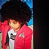 Legend is registered to the contest to win money with this photo: child, curly_hair, red_jacket, nike_air, white_tshirt, indoor, portrait, looking_down, casual_clothing, person, young_child, afro_hairstyle, fashion, clothing, tile_floor, screen_photo, technology, blue_background, expression, curious