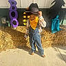 Legend joined the competition — help win amazing prizes! child, boy, cowboy_hat, yellow_bandana, denim_overalls, plaid_shirt, hay, sidewalk, halloween_decorations, boo_sign, ghost_cutout, witch_silhouette, outdoor, sunny, costume, fall, holiday, shy, portrait, decor