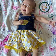 Inaya is registered to the contest to win money with this photo: baby, infant, smiling, happy, clothing, dress, denim, pattern, blanket, butterfly, giraffe, milestone, 2_month, cute, lying_down, skin, arm, head, face, person