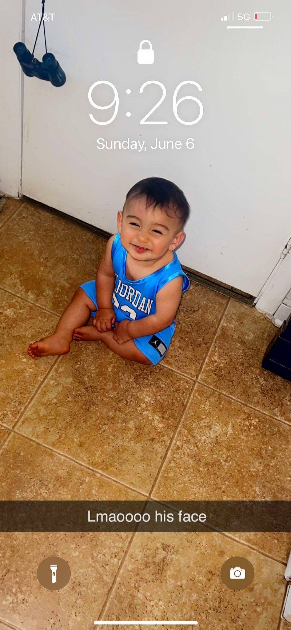 Kenzo is registered to the contest to win money with this photo: baby, baby_toddler_clothing, child, eye, finger, floor, flooring, font, fun, happy, hardwood, joy, logo, person, room, sitting, skin, sleeve, smile, t_shirt
