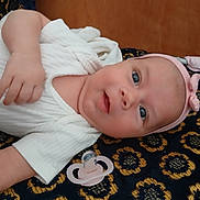 Lilly participe au concours pour gagner de l'argent avec cette photo : baby, infant, pacifier, headband, white_clothing, blue_eyes, lying_down, patterned_blanket, cute, child, portrait, indoor, soft_light, hand, face, skin, newborn, young_child, resting, pink