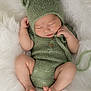 baby, sleeping, knitted_hat, knitted_outfit, green_clothing, infant, newborn, fluffy_blanket, soft_texture, cute, peaceful, portrait, closeup, tiny_feet, tiny_hands, cozy, resting, indoors, child, adorable