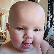 Ember joined the competition — help win amazing prizes! baby, child, face, blue_eyes, indoor, cheeks, smiling, close_up, skin, person, infant, expression, curtains, furniture, dining_chair, door, window, home, light, tongue
