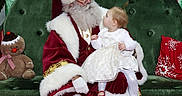 Savannah joined the competition — help win amazing prizes! child, baby, santa_claus, christmas, holiday, presents, gifts, festive, portrait, sitting, lap, beard, santa_hat, red_suit, white_dress, gingerbread_toy, couch, decorations, indoor, smiling