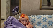 Daphne joined the competition — help win amazing prizes! baby, blanket, child, couch, cozy, curious, flower_pattern, foot, furniture, headband, indoor, infant, mirror, orange, person, pillow, purple, reflection, seated, soft_texture