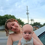 Daphne is registered to the contest to win money with this photo: baby, child, woman, portrait, outdoor, smile, happy, holding, person, face, head, skin, clothing, nature, car, trees, daylight, casual, cute, family