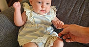 Daphne is registered to the contest to win money with this photo: baby, child, infant, girl, dress, headband, bow, sitting, hand, finger, armchair, furniture, indoor, cute, portrait, person, skin, expression, comfort, holding