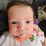 Arya is registered to the contest to win money with this photo: baby, infant, closeup, face, eyes, onesie, clothing, expression, hair, pout, person, carpet, furniture, indoor, child, cute, skin, head, portrait, toddler